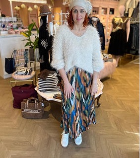 Cliente essayant un ensemble coloré sur le plancher chevron de la boutique